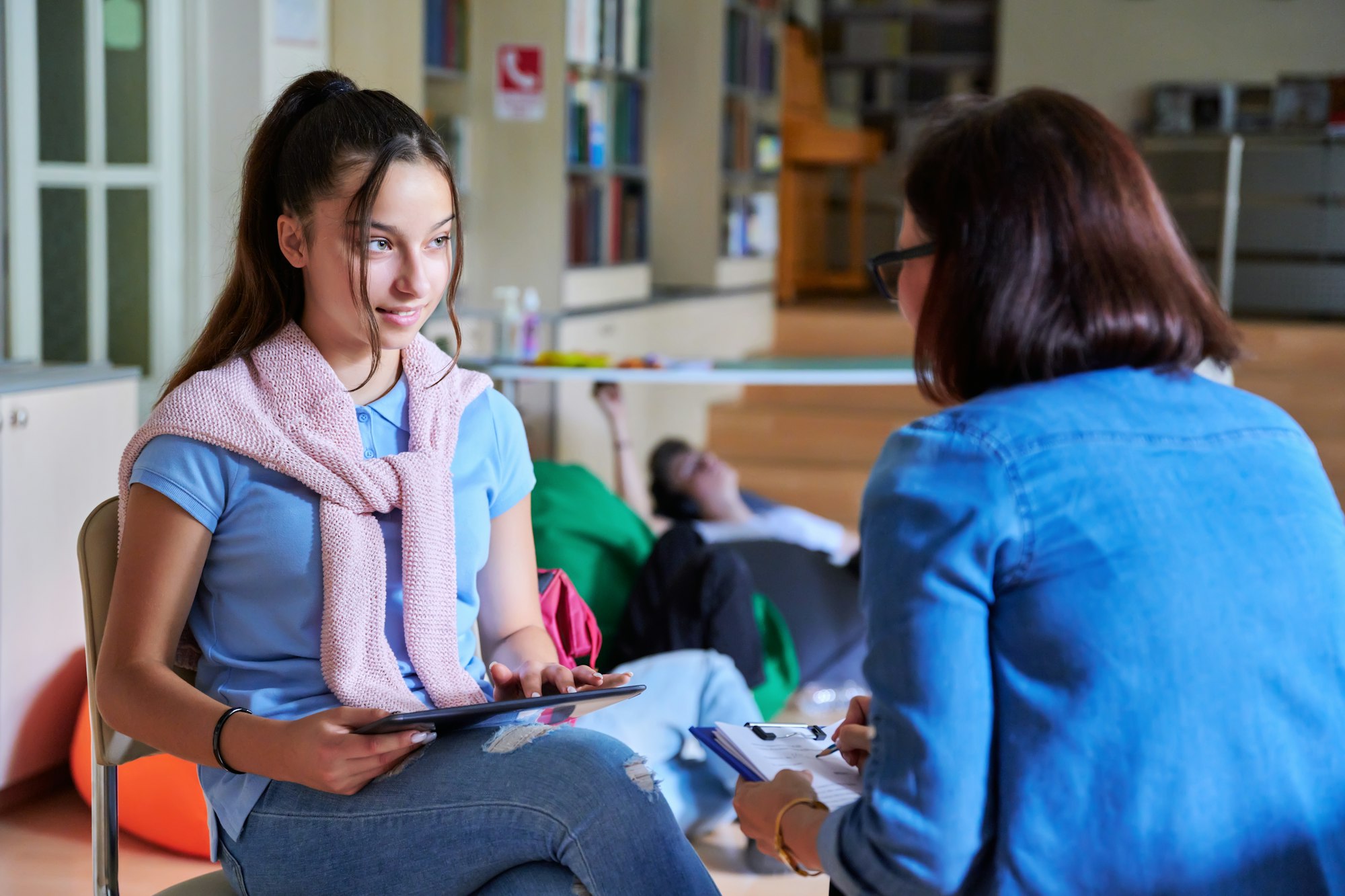 Woman school psychologist teacher talking and helping student, girl teenager