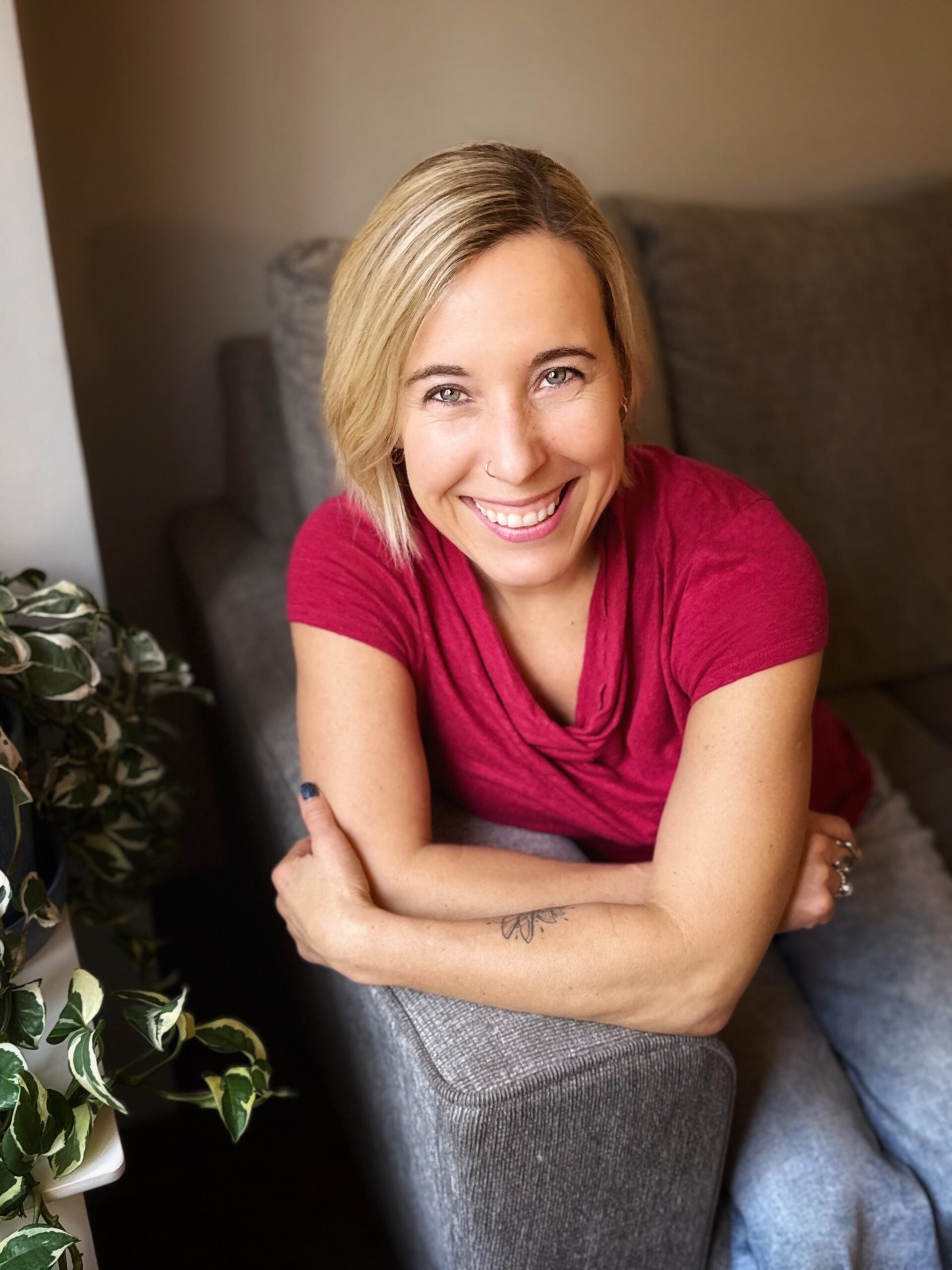A happy smiling blonde woman leans on a chair